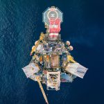 Vista aérea de uma plataforma de petróleo offshore cercada pelo mar.