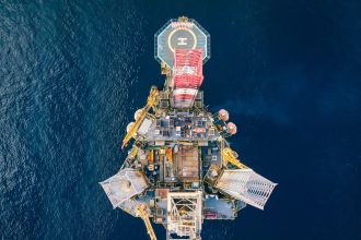 Vista aérea de uma plataforma de petróleo offshore cercada pelo mar.