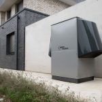 Sistema de bomba de calor instalado na área externa de um edifício contemporâneo.