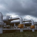 Tubulações e válvulas metálicas de uma instalação industrial de gás sob céu nublado.