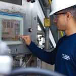 Profissional opera um painel de controle em uma instalação industrial.
