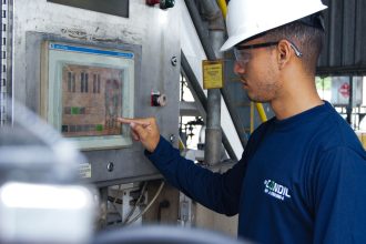 Profissional opera um painel de controle em uma instalação industrial.